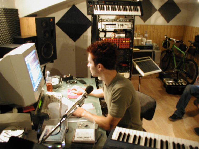 Blick auf Studiocomputer, Keyboard, Mikrofon und Rackgeräte am Regieplatz.
